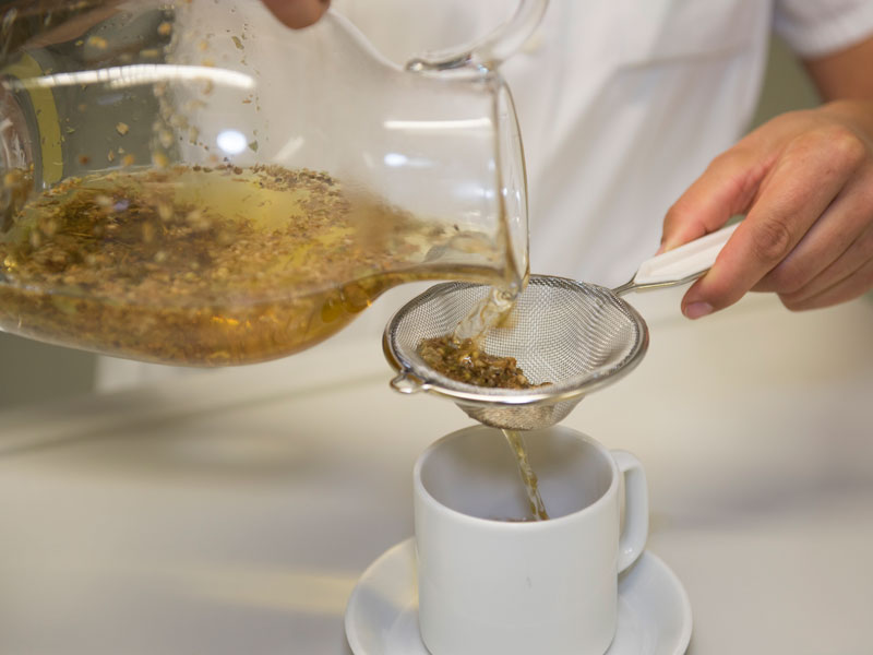 Lungenerkrankungen Tee wird durch Sieb in Tasse geschüttet KfN München