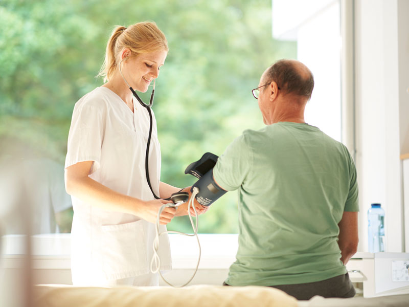 Pflegerin misst Blutdruck bei Patienten KfN München