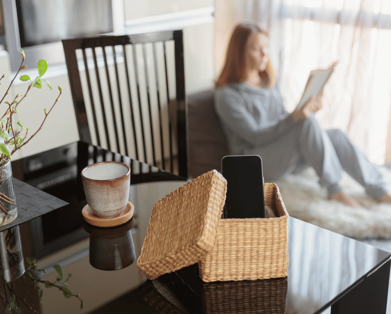 Frau liest etwas, während sie ihr Handy in eine Kiste gepackt hat für einen Digital Detox